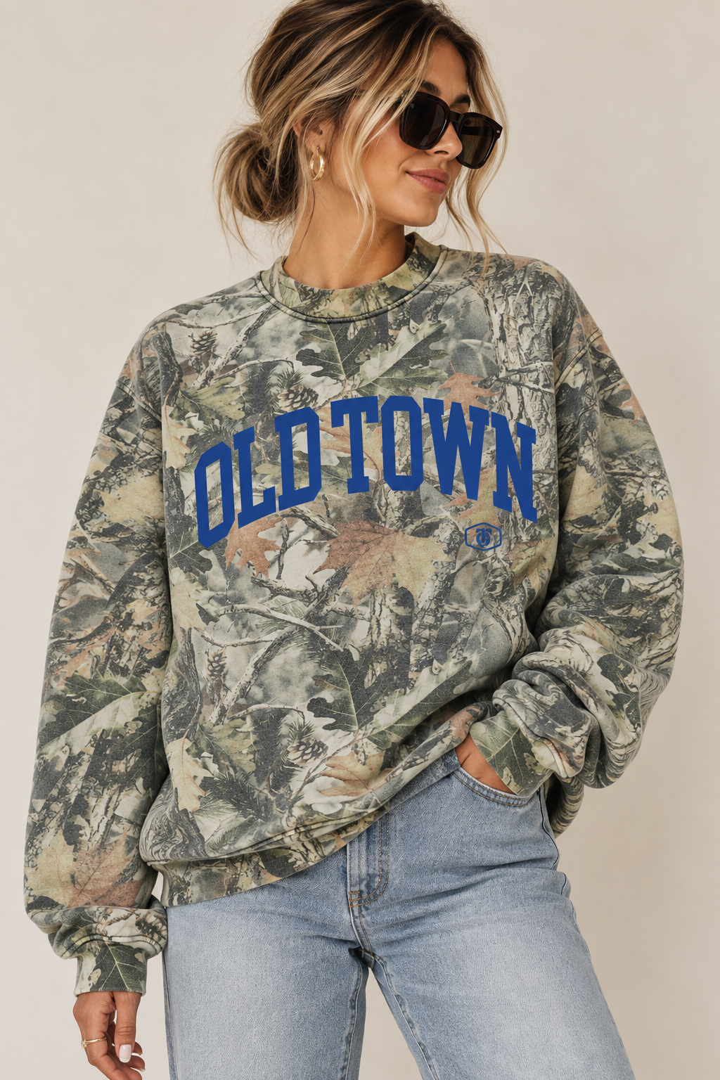 Woman wearing custom oversized woodland camo heavyweight crewneck sweatshirt with royal blue OLD TOWN collegiate lettering